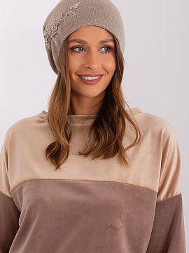 Cap AT  Warm women\'s winter hat made of smooth knit fabric with decorative applique on the side.