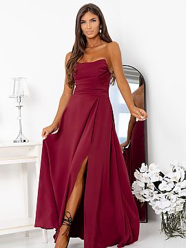 Long gown With You  A long dress made of smooth, shiny fabric. A model with detachable straps, with a delicately ruched top and a striking, high slit on the leg